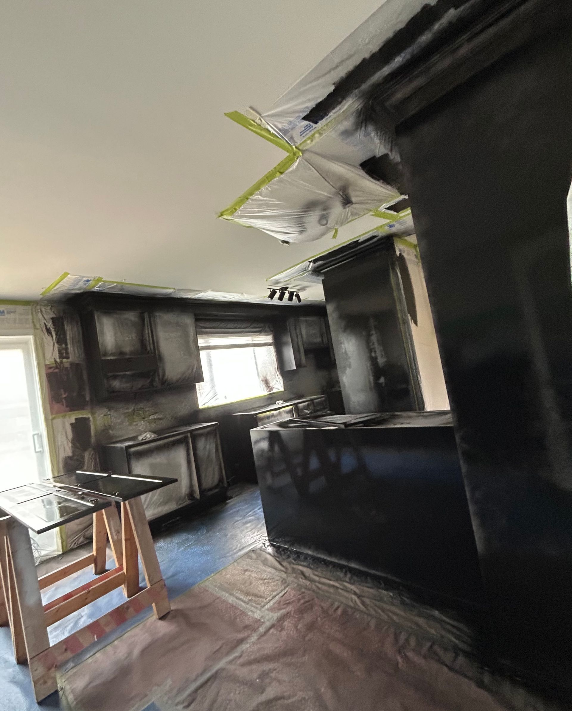 
A kitchen is being painted black and covered in plastic.
Une cuisine est peinte en noir et recouverte de plastique.