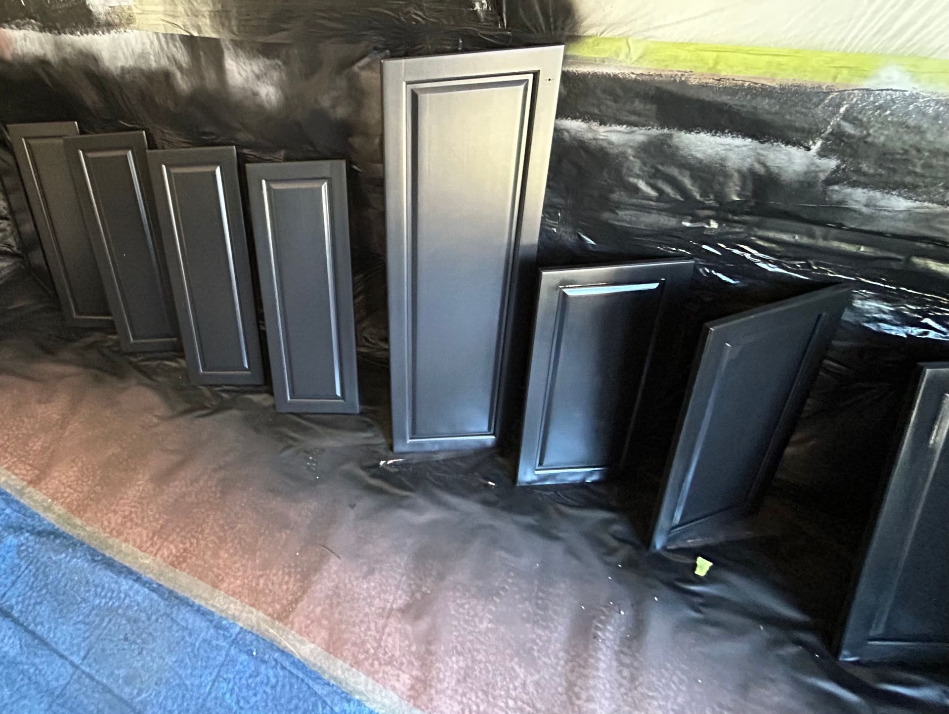 Un tas de portes d’armoires noires sont posées sur une table.