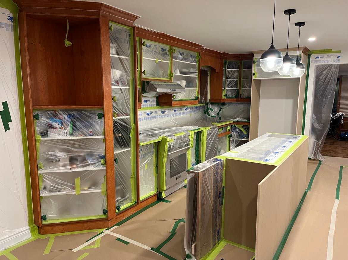 A kitchen is being painted and covered in plastic.