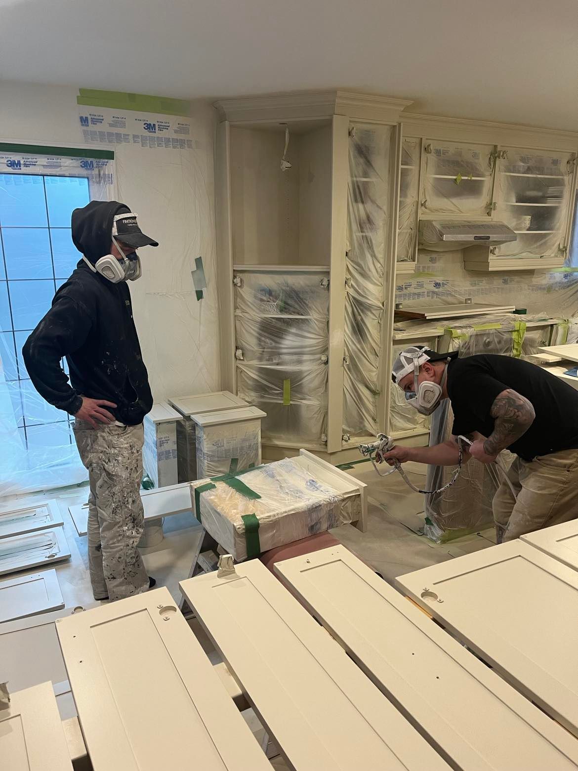 A man is standing on a ladder painting the side of a house.