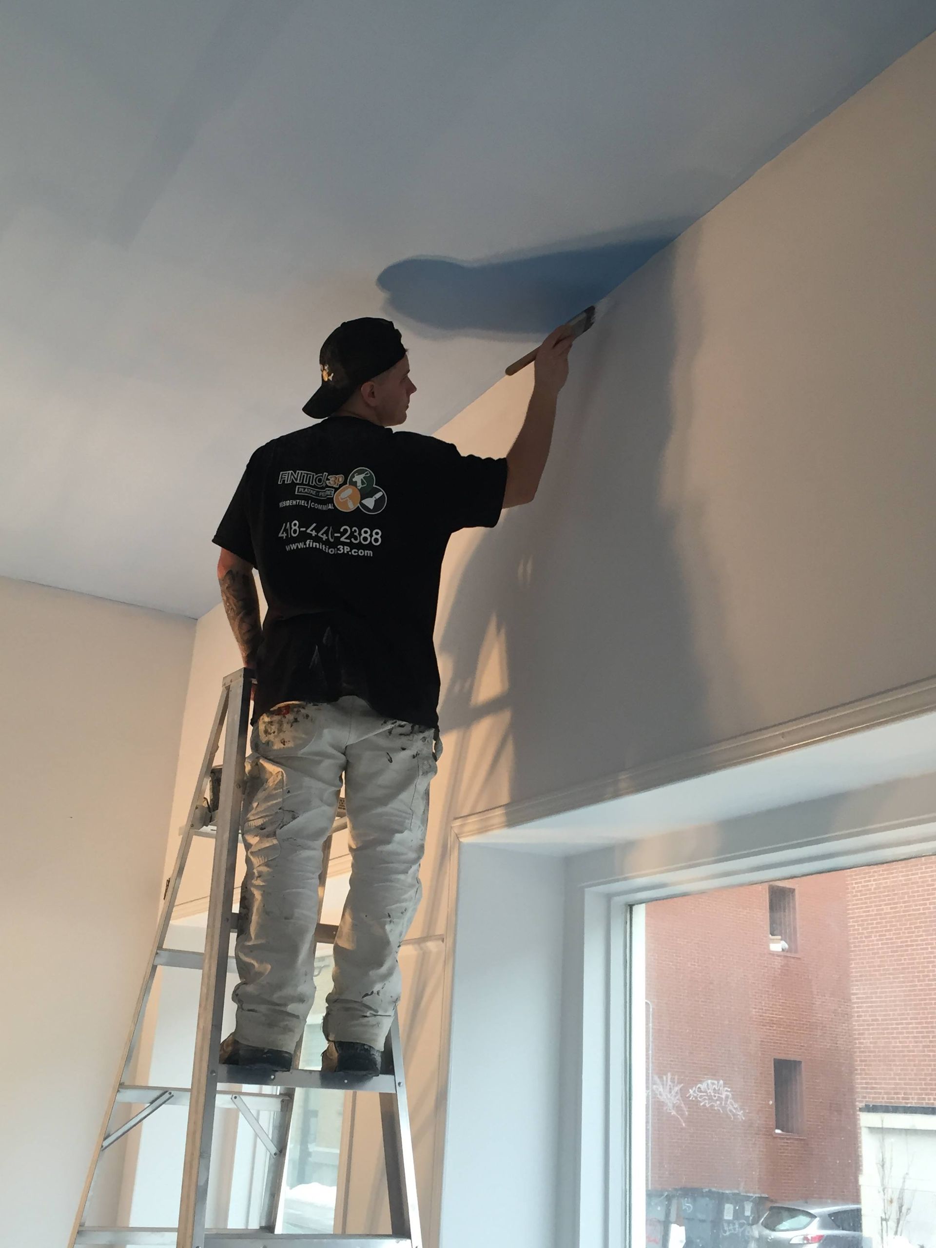 A man standing on a ladder painting a wall