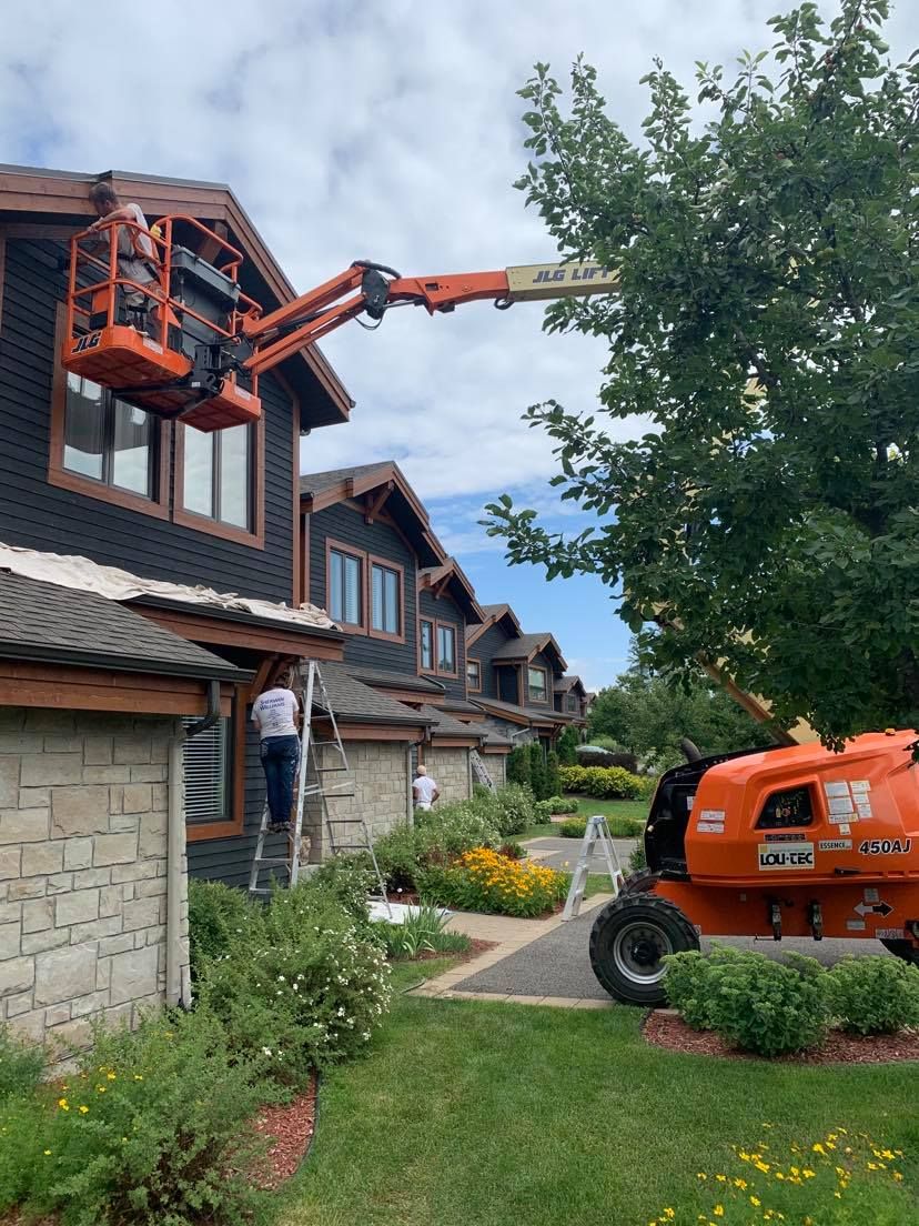 A man is painting a house with a lift.
