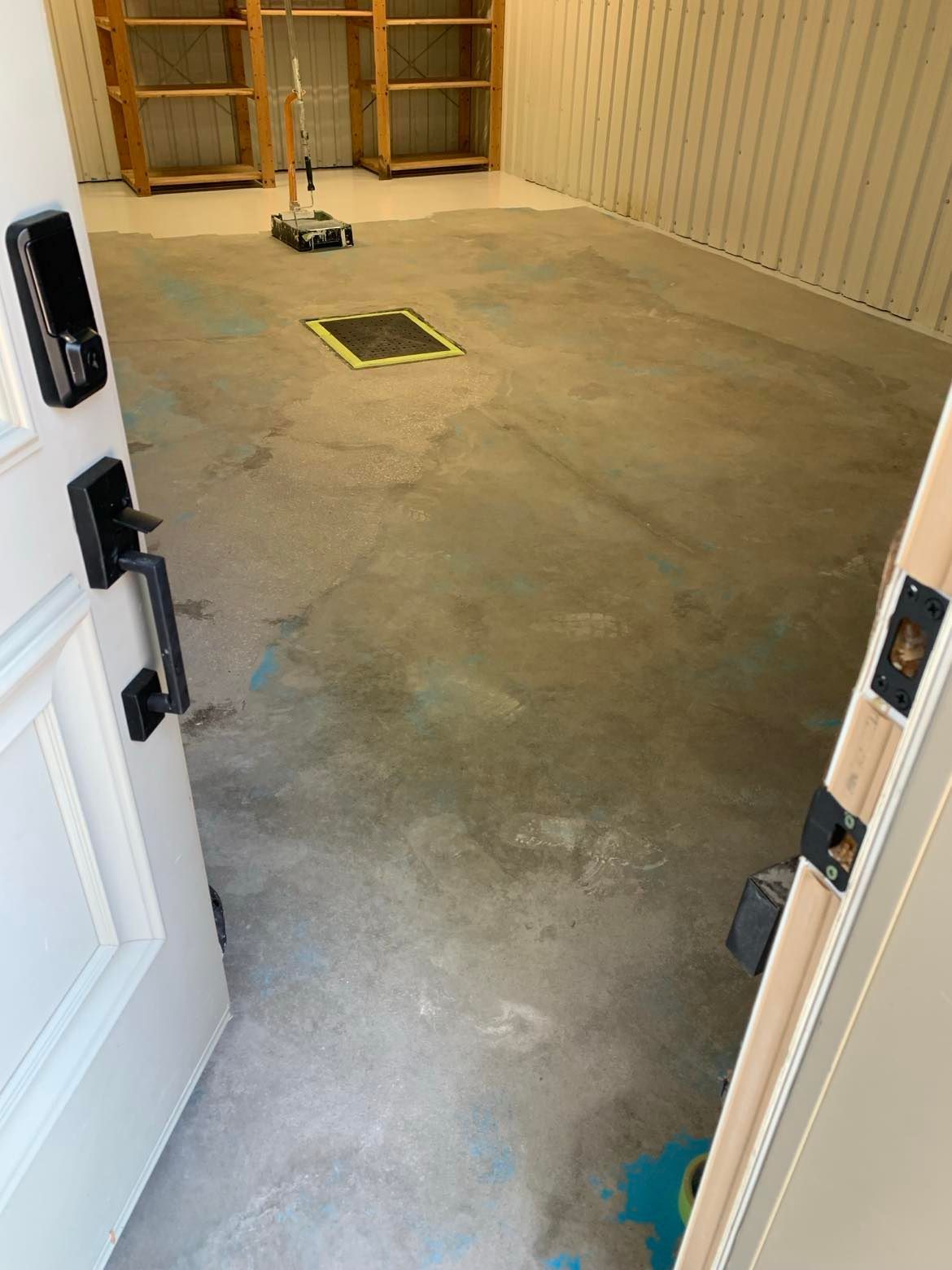 A door is open to a room with a concrete floor and shelves.