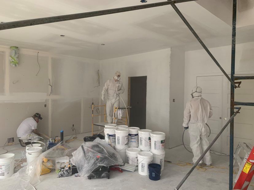 A man is standing on a ladder painting the side of a house.