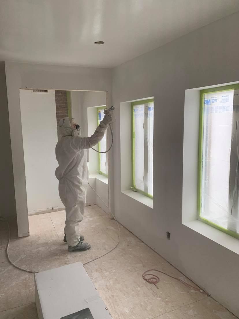 A man in a protective suit is spray painting a wall.