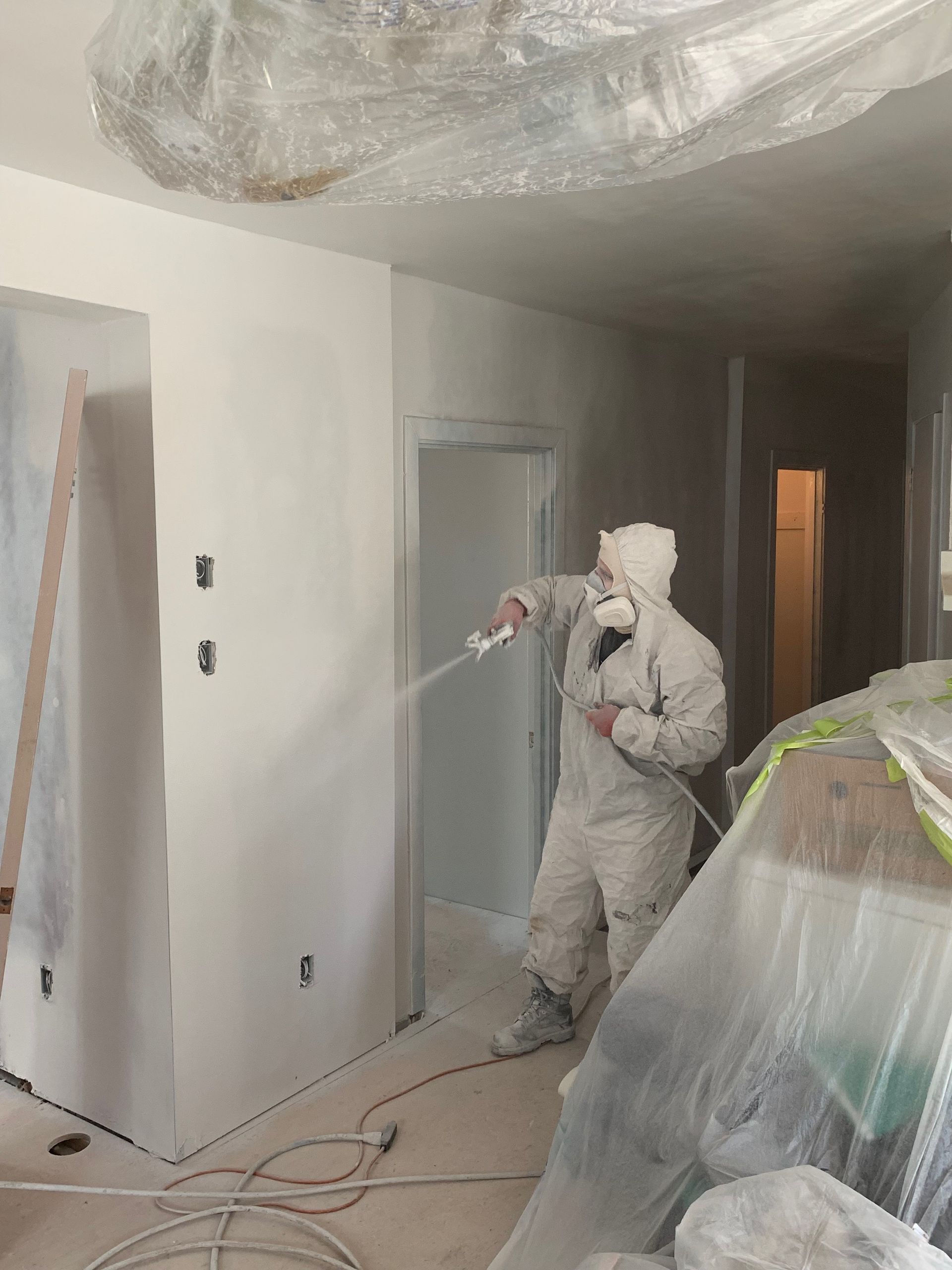 A man is spraying paint on a wall in a room.