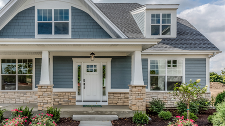 Blue and stone home with white trim, front porch, and landscaping.