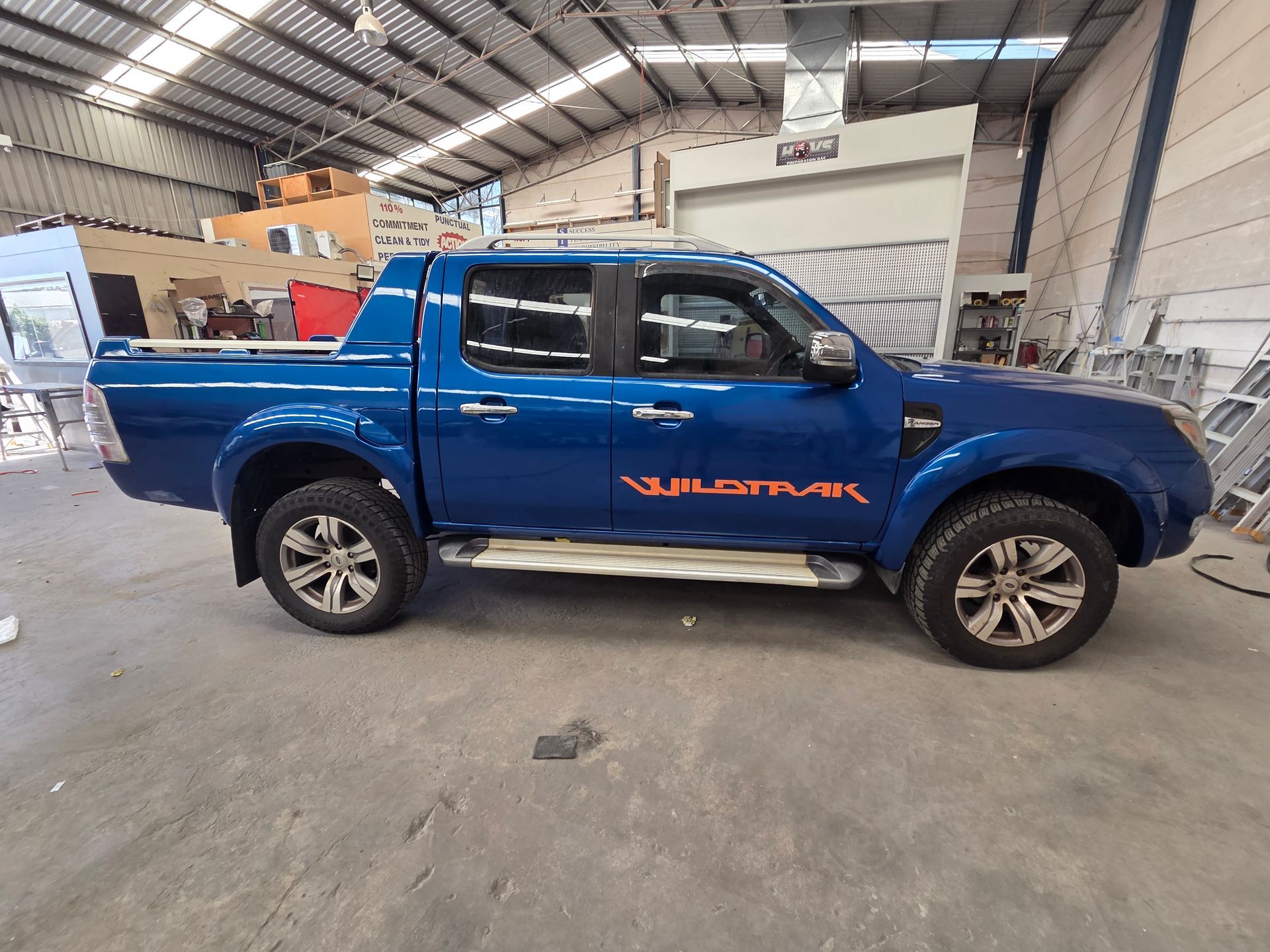 Blue pickup truck with orange lettering parked inside an industrial warehouse — A2B Smash Repairs in Berkeley Vale, NSW