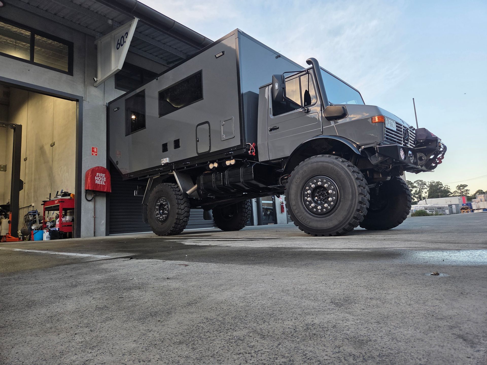 Lifted black overland truck parked outside a garage, viewed from a low angle — A2B Smash Repairs in Berkeley Vale, NSW