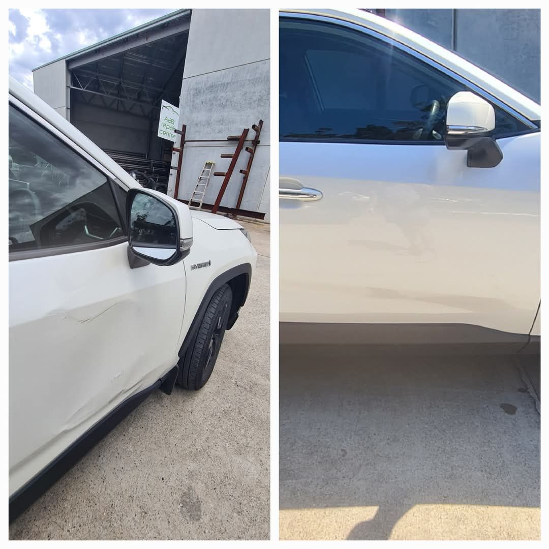 White SUV by a garage, showing damage to the side mirror and front door panel — A2B Smash Repairs in Berkeley Vale, NSW
