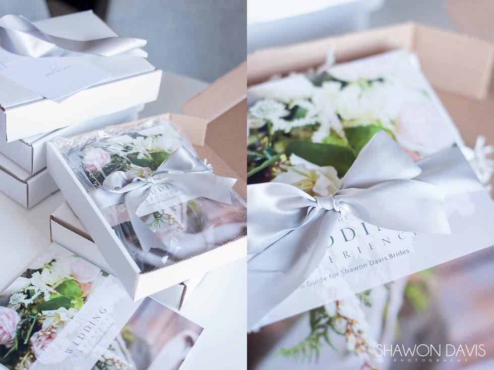White gift boxes filled with white floral arrangements and ribbon bows on a soft blue surface