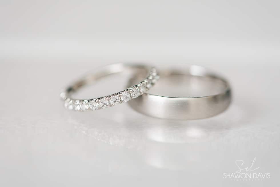 Two silver wedding bands, one with small diamonds, on a soft white background