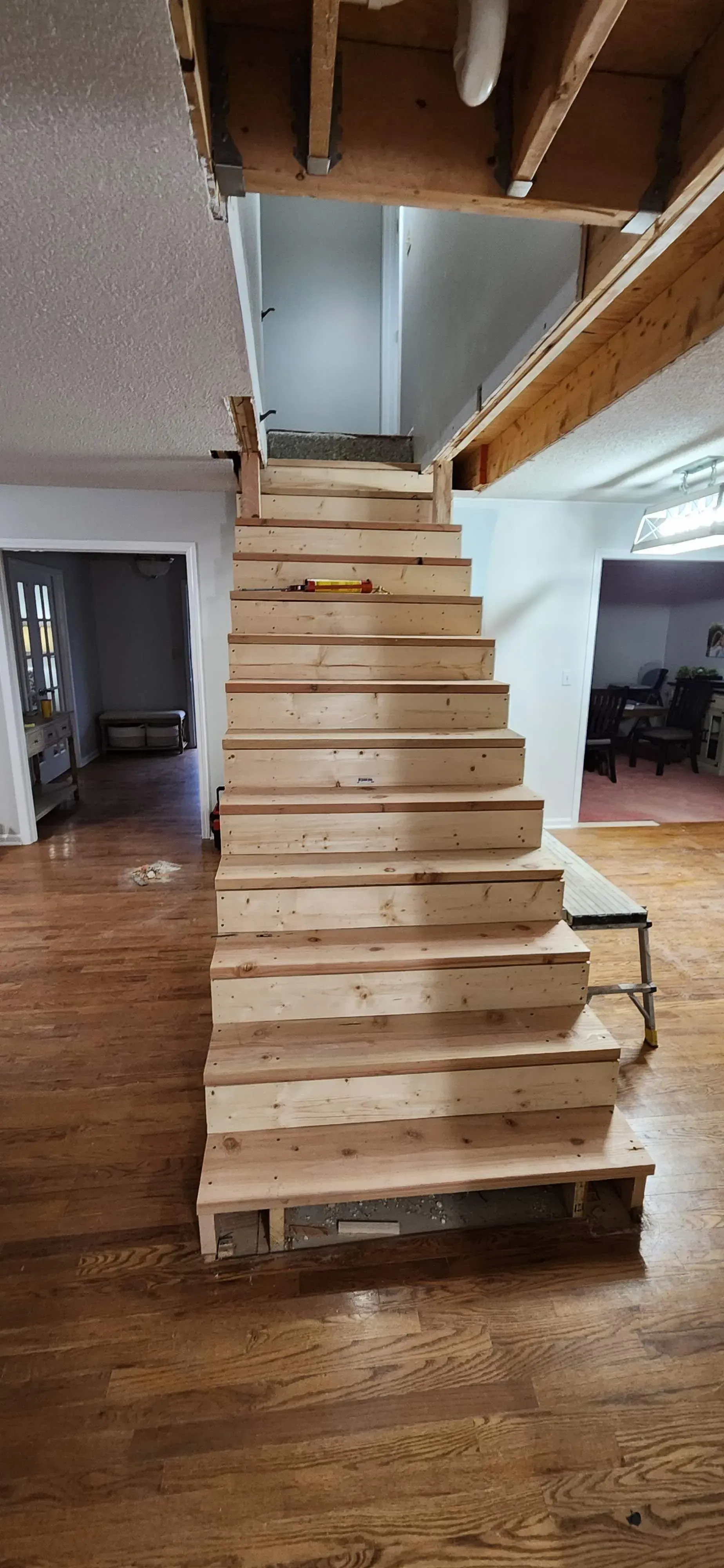 A wooden staircase is being built in a house.