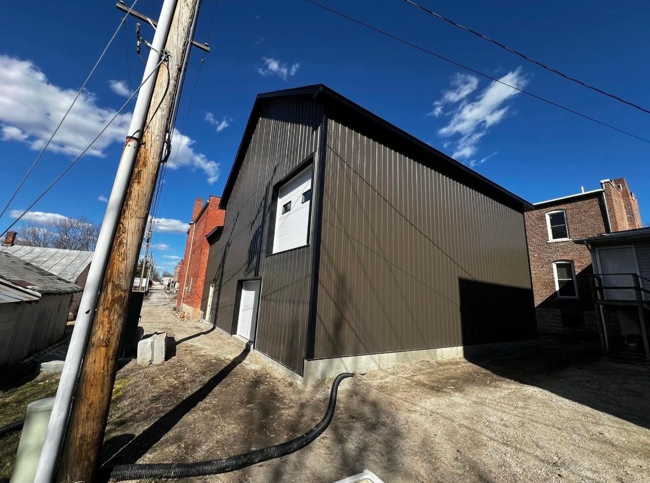 A large brown building with a garage door and a telephone pole in front of it.