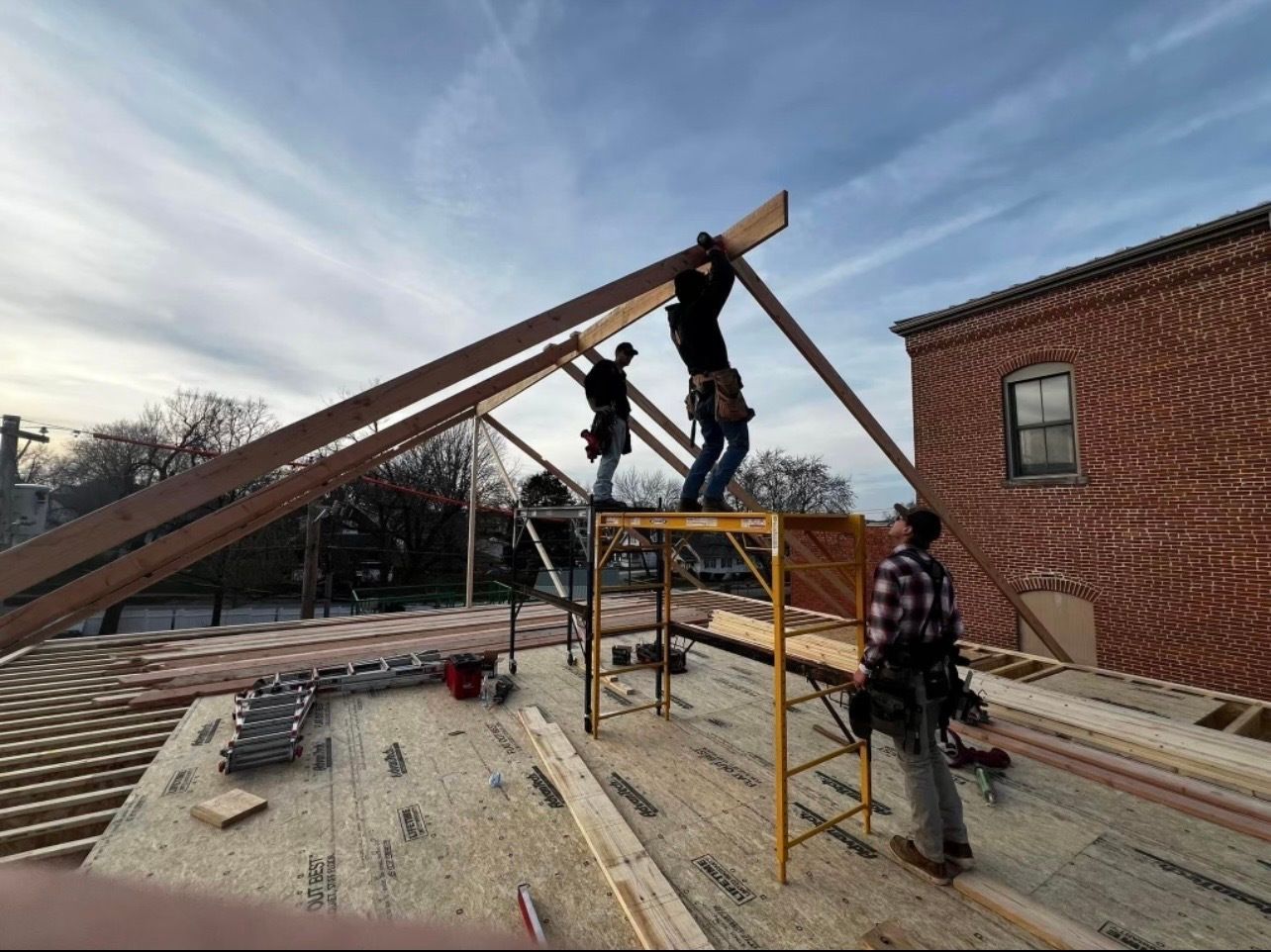 A group of construction workers are working on the roof of a building.