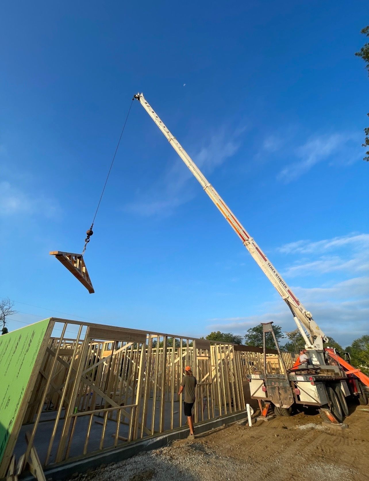 A crane is lifting a piece of wood on a construction site.