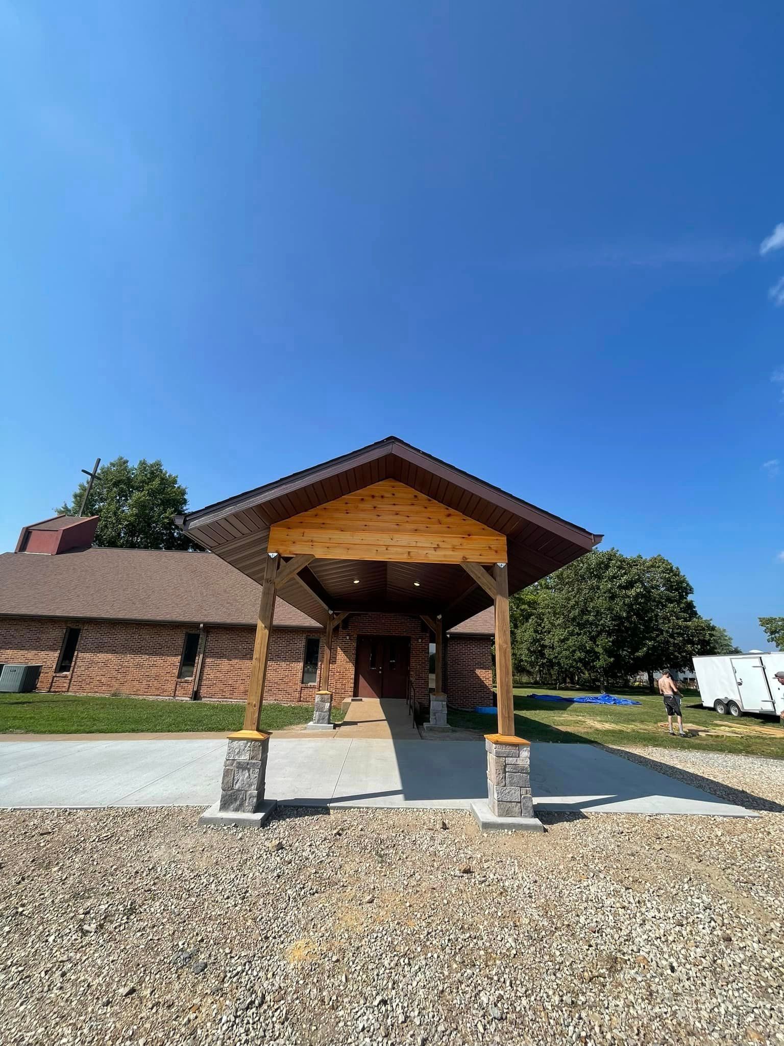 A house with a wooden porch and a brick building in the background.