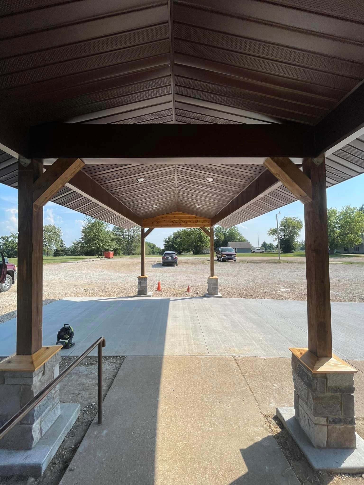 A view of a parking lot from inside a wooden structure.