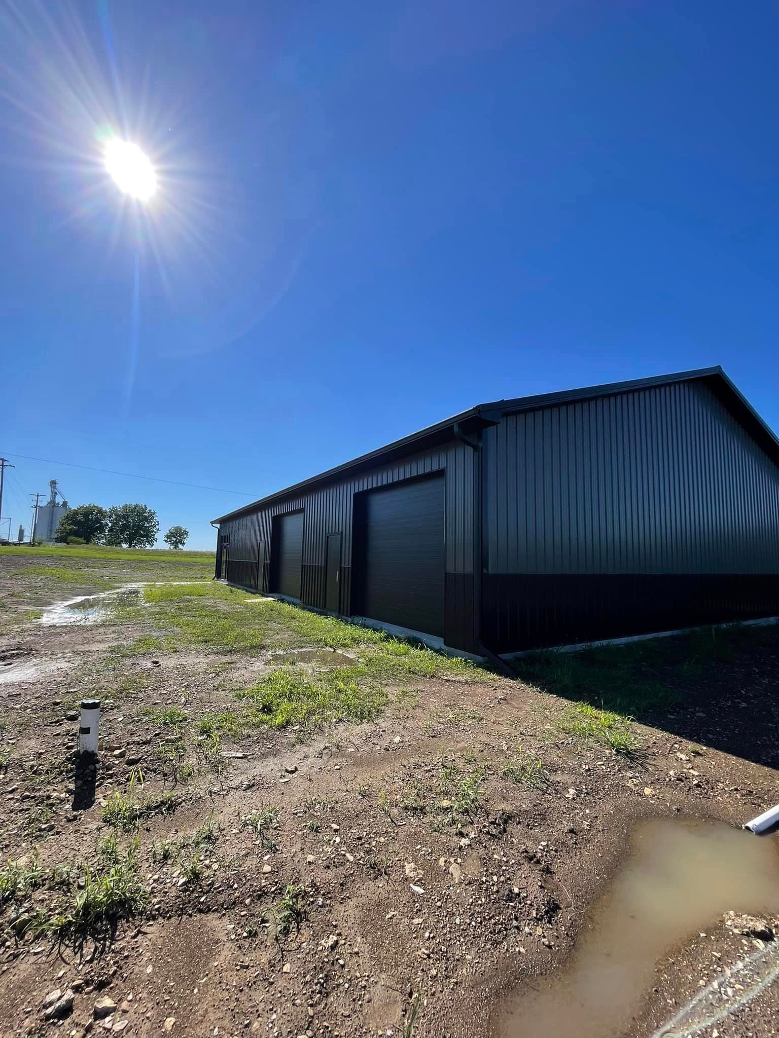 A large black building is sitting on top of a dirt field.