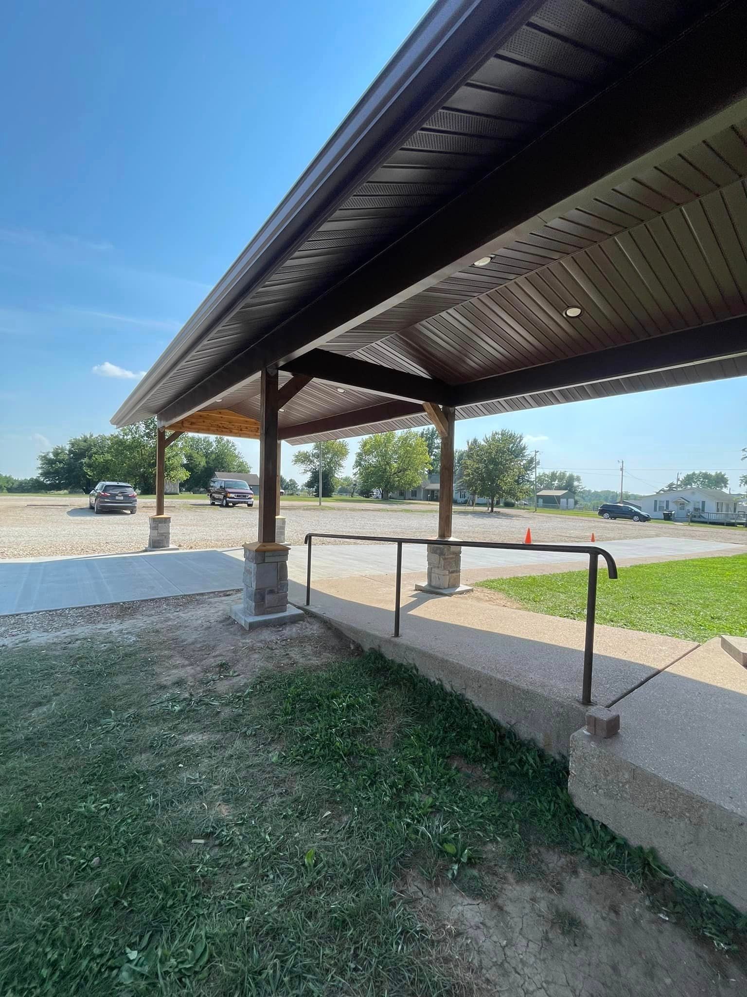 A covered walkway with a railing leading to a parking lot.
