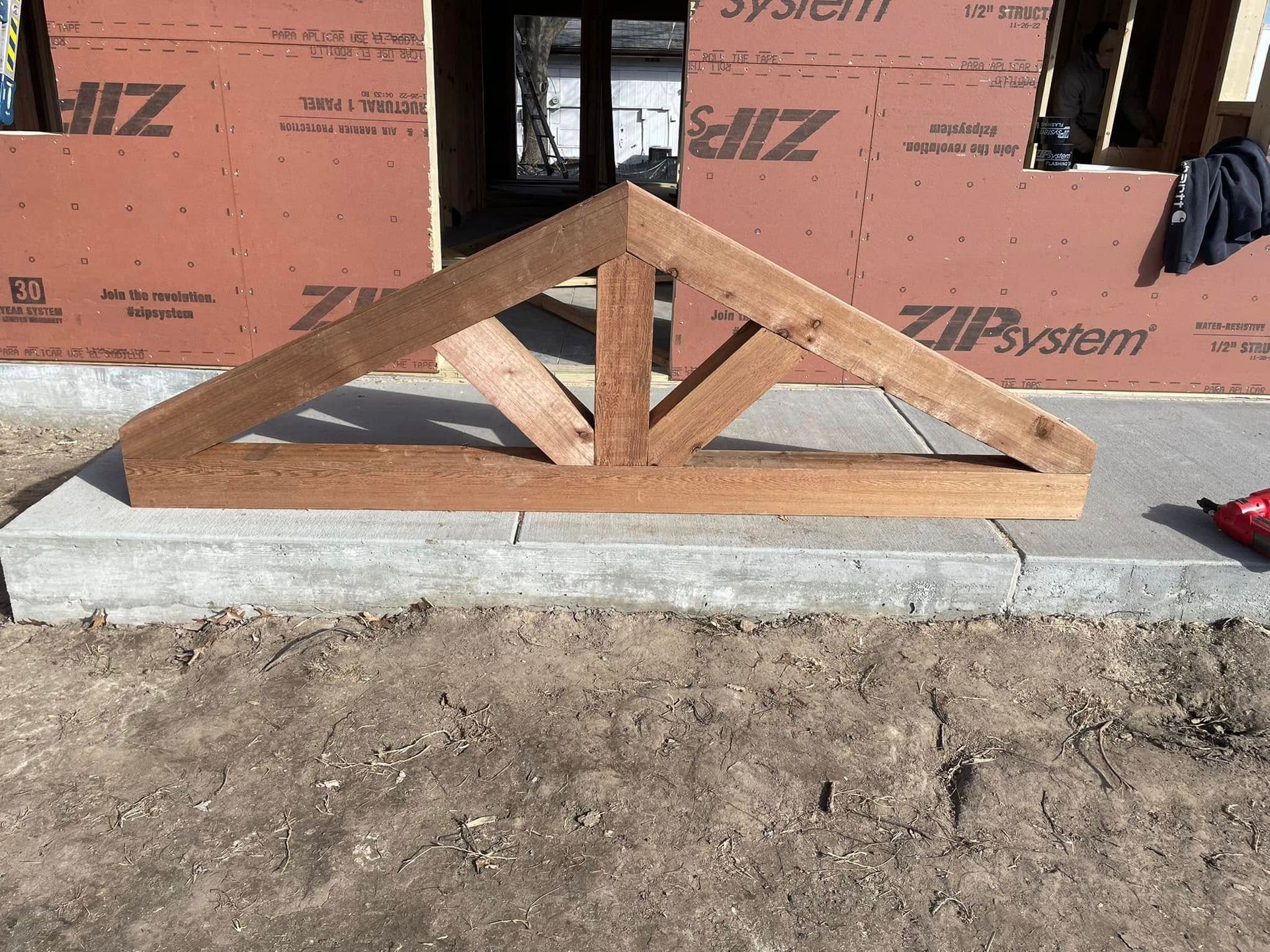 Wooden roof truss on concrete, construction site setting.