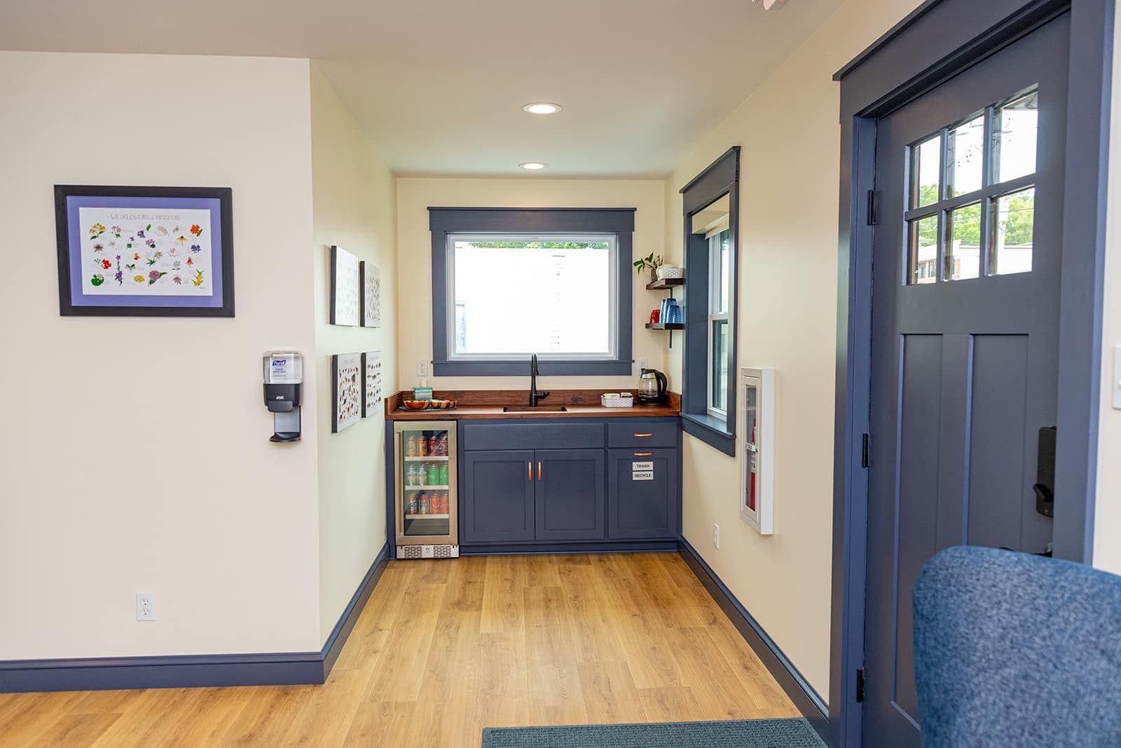 Hallway with blue cabinetry, window, and door; neutral walls, wood flooring.