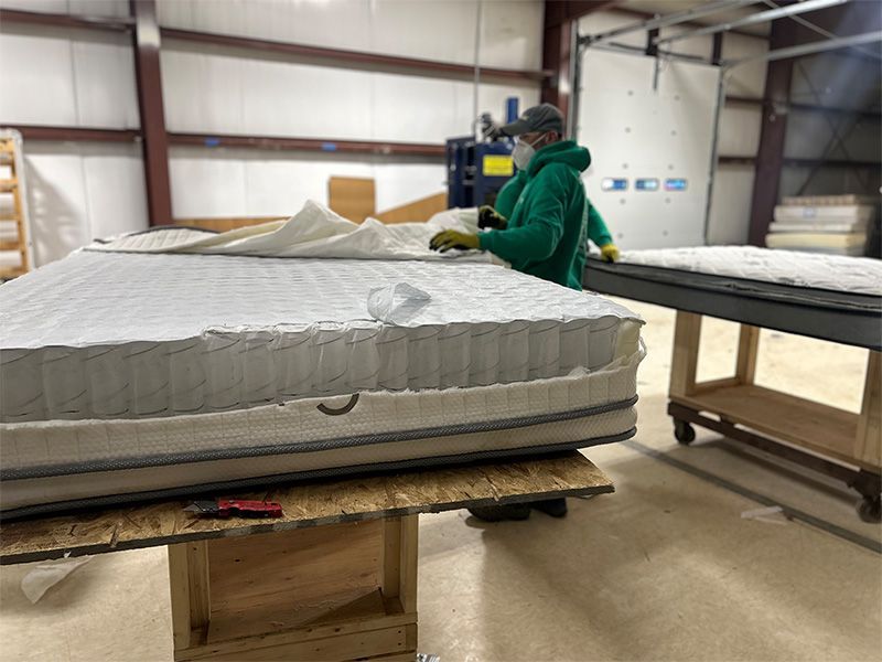 A man is working on a mattress in a factory.