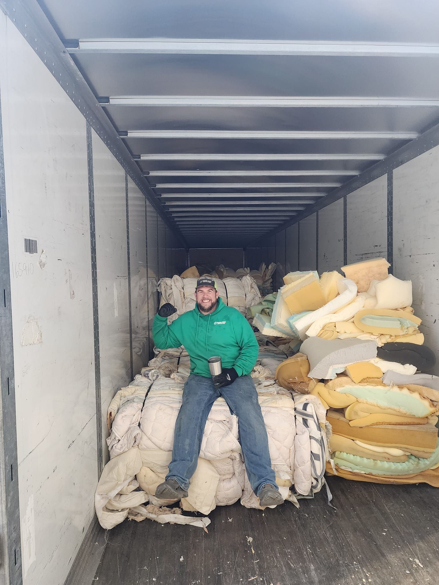 A man is sitting on a pile of foam in a truck.