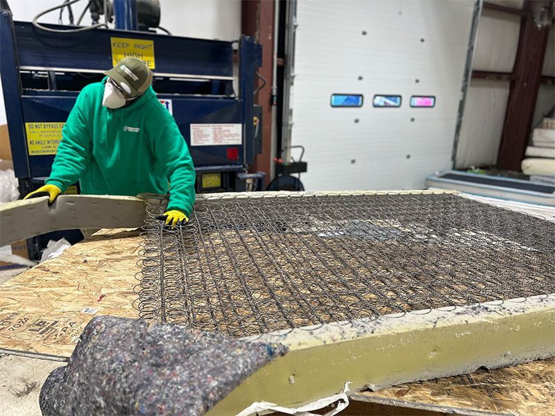 A man in a green shirt is working on a mattress