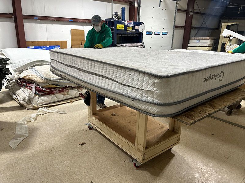 A man is working on a mattress in a factory.