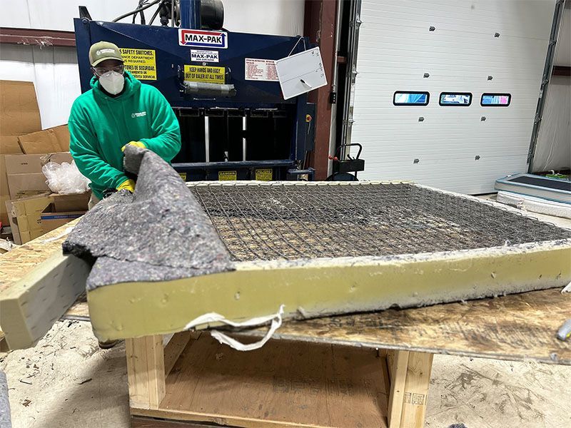 A man wearing a mask is standing next to a large piece of foam.