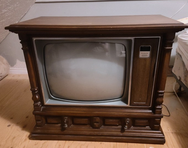 An antique wooden television set in a wooden cabinet, brown with a large gray screen.