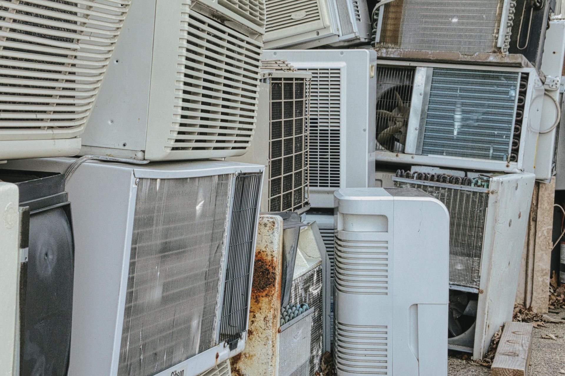 A pile of old air conditioners are stacked on top of each other.