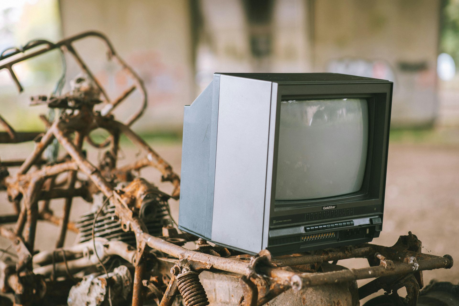 An old television is sitting on top of a rusty piece of metal.