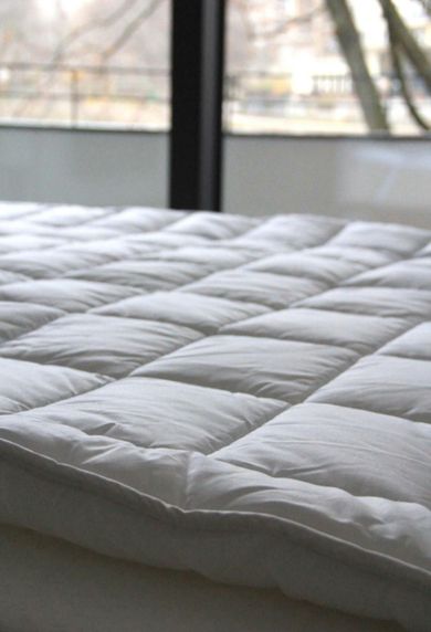 A bed with a white comforter and a window in the background
