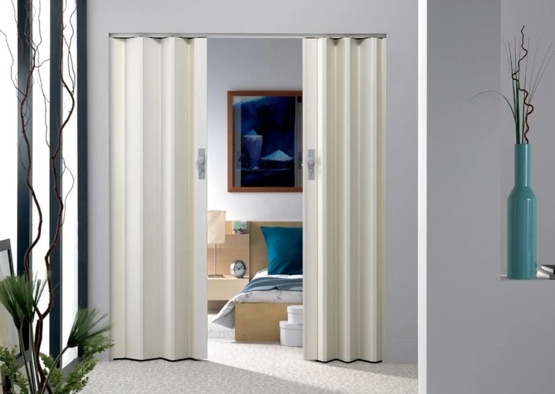 Le porte beige a soffietto si aprono su una camera da letto con un letto, un'opera d'arte e un comodino.