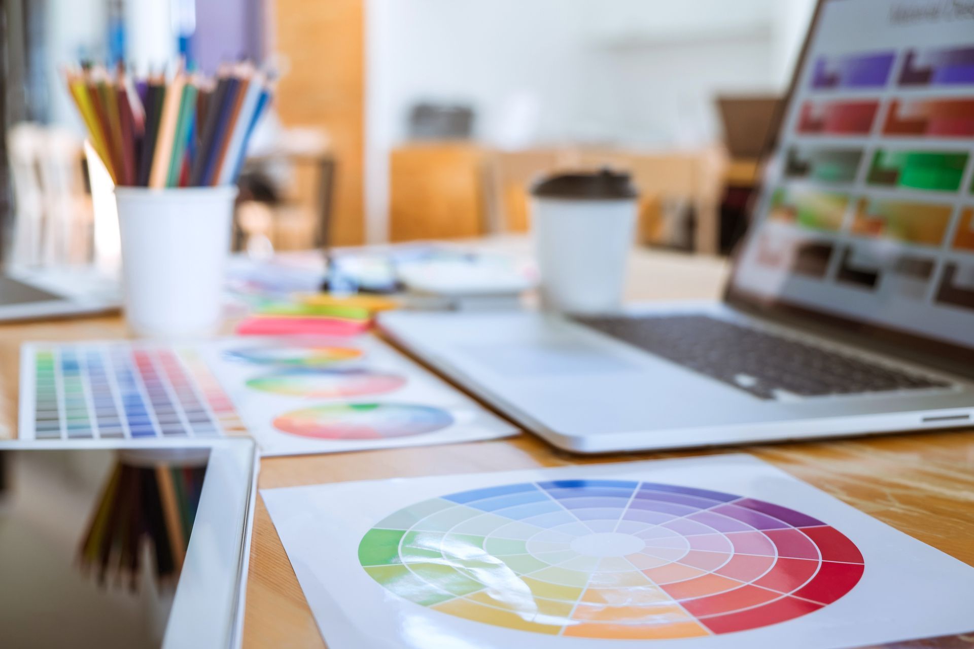Una scrivania con un laptop, un tablet e una ruota dei colori.