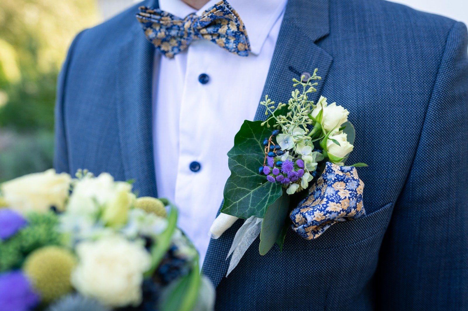 Brosche und blumige Hochzeitskleider auf Bräutigam