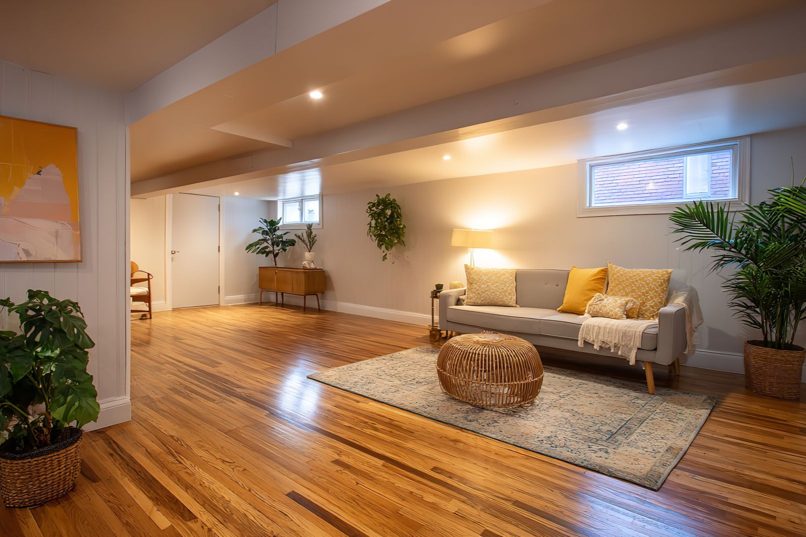 Cozy living room with wood floors, neutral sofa, plants, and natural light.