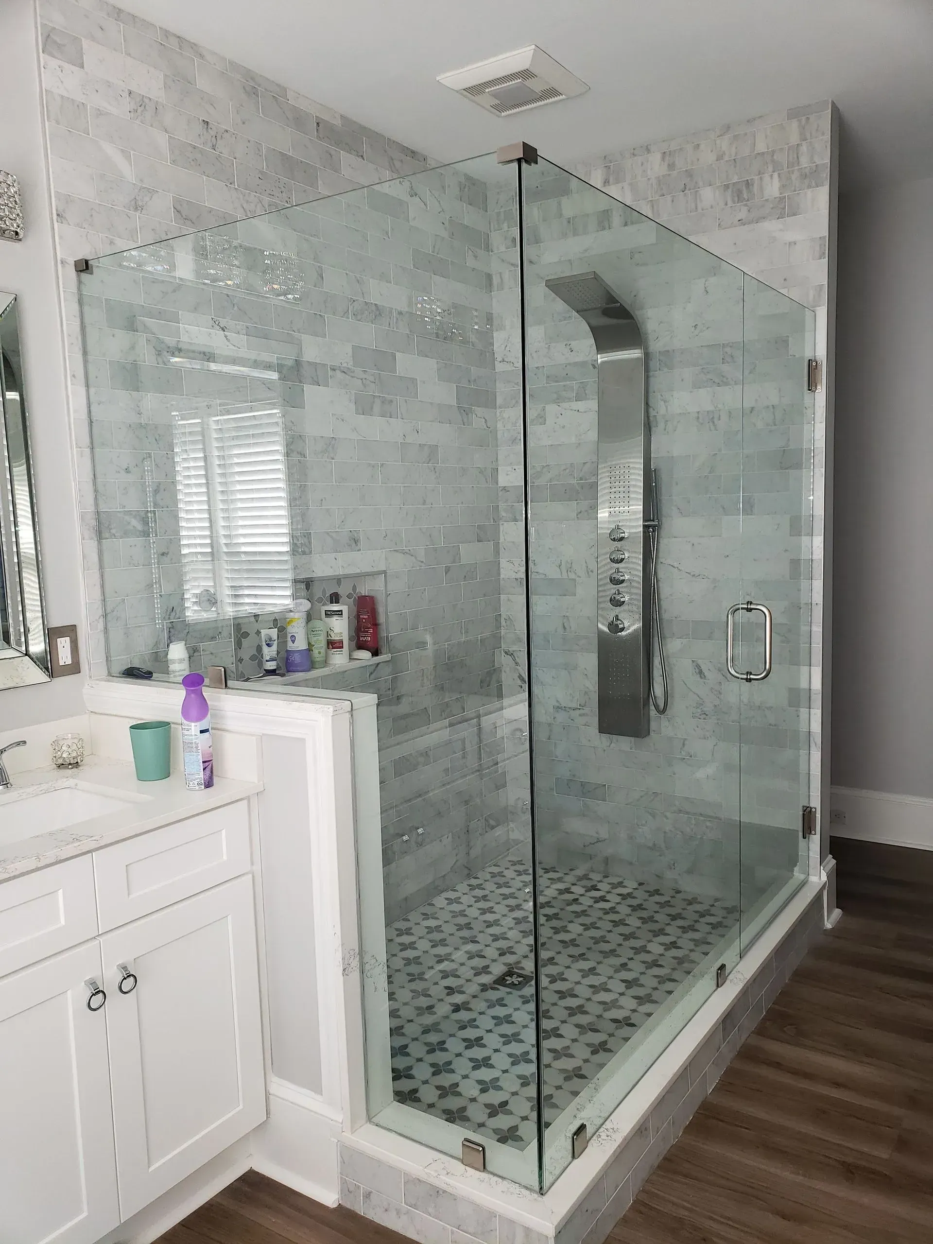 Modern shower with glass walls, tiled interior, and silver shower fixtures.