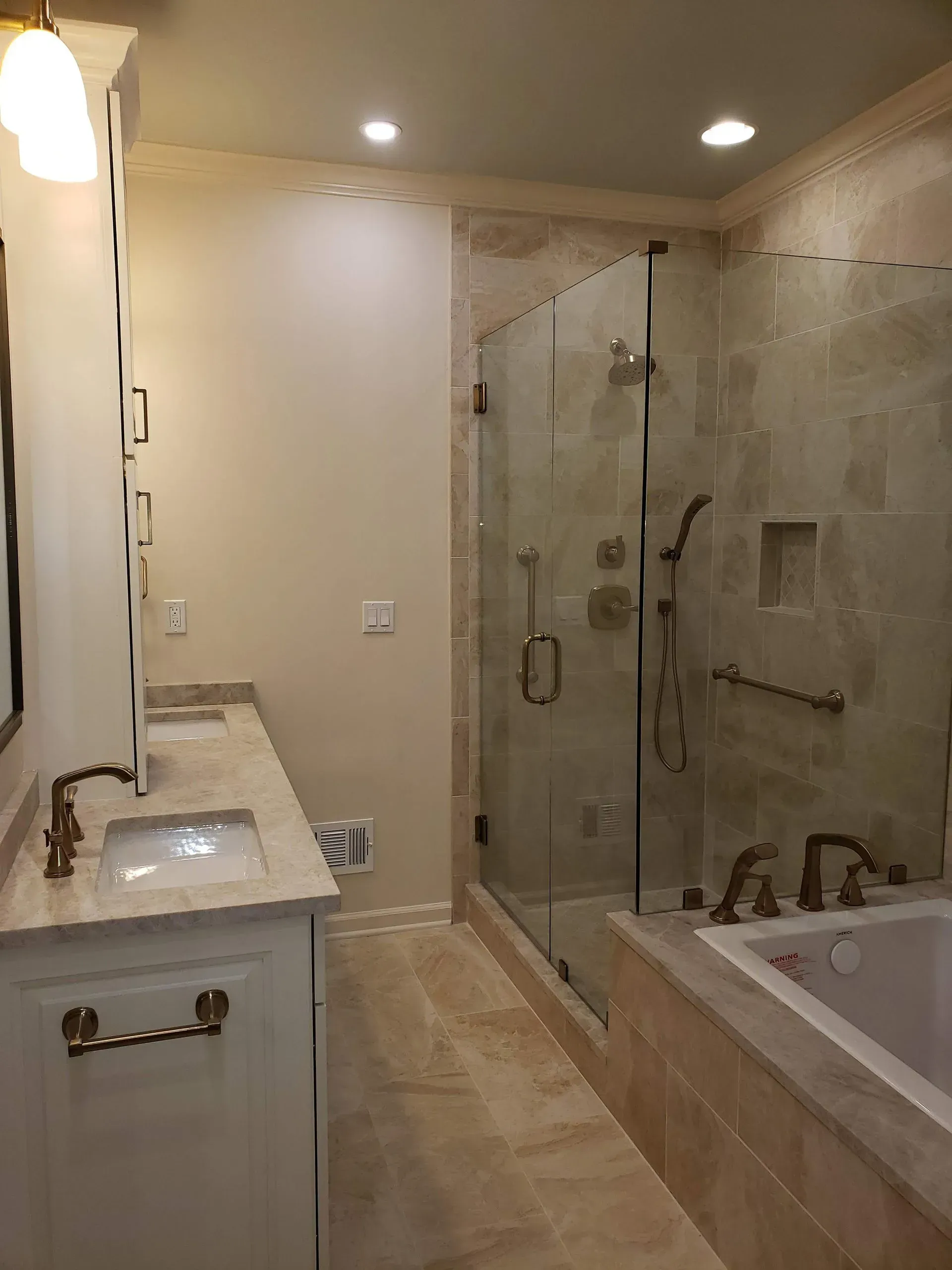 Bathroom with a white vanity, a glass shower, and a built-in bathtub, all with beige tiles.