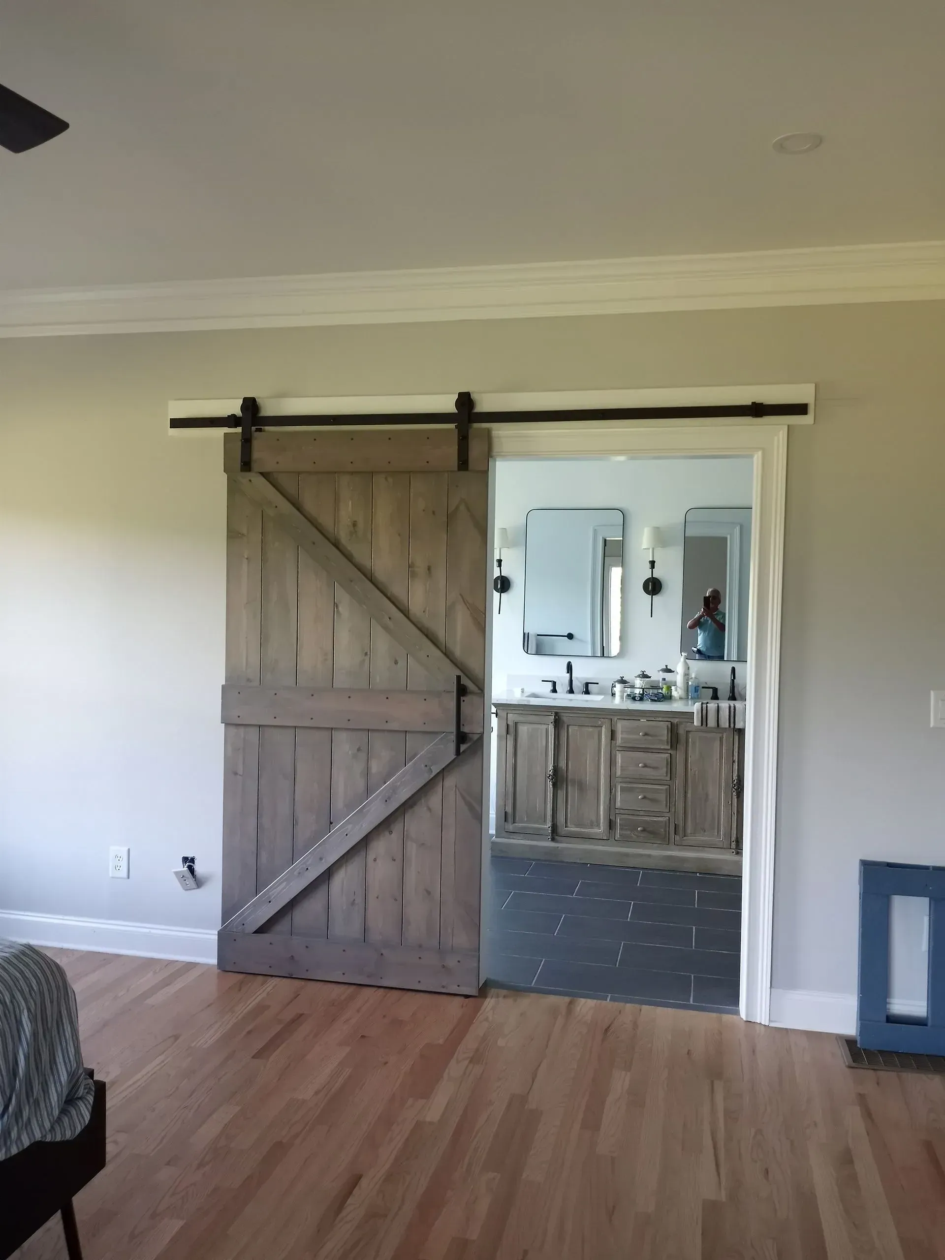 Barn door partially open, revealing a bathroom with a rustic vanity and mirror.