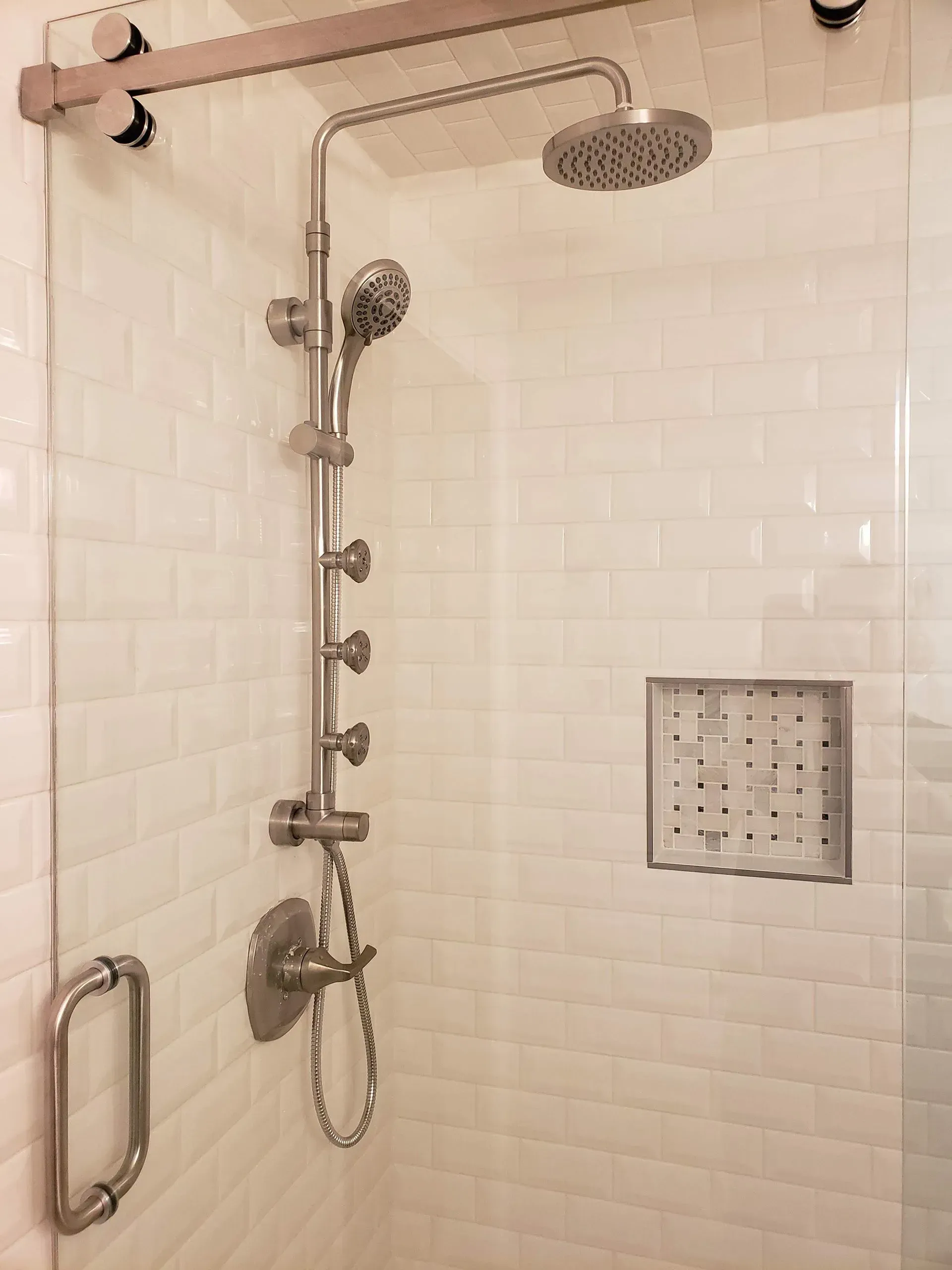 Shower stall with glass door, subway tile, and silver shower fixtures.