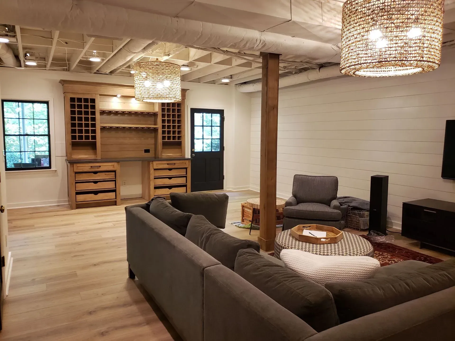 Spacious finished basement with wood accents, gray sectional, and a built-in bar.
