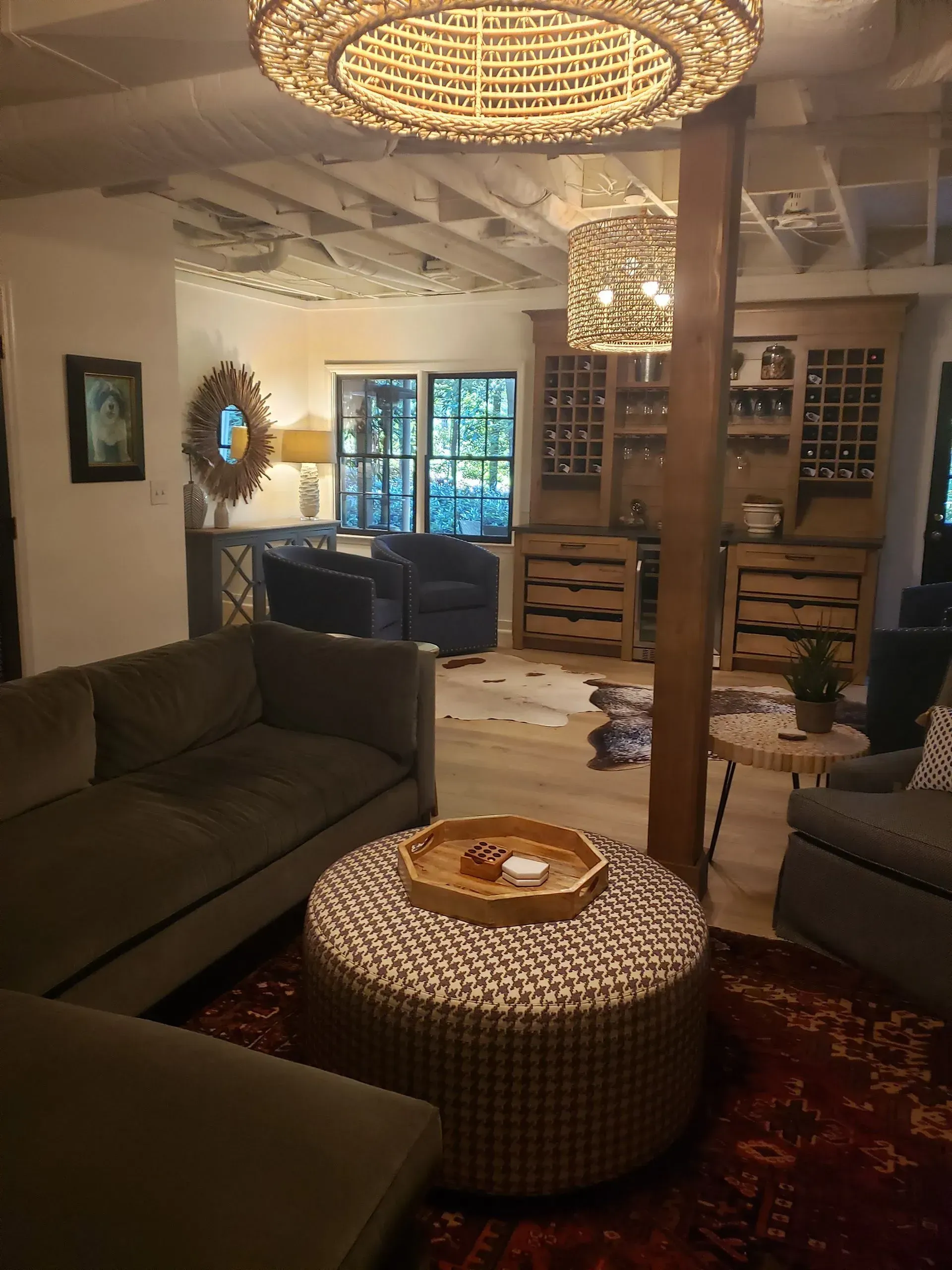 Living room with a sofa, ottoman, area rug, bar, and light fixtures.