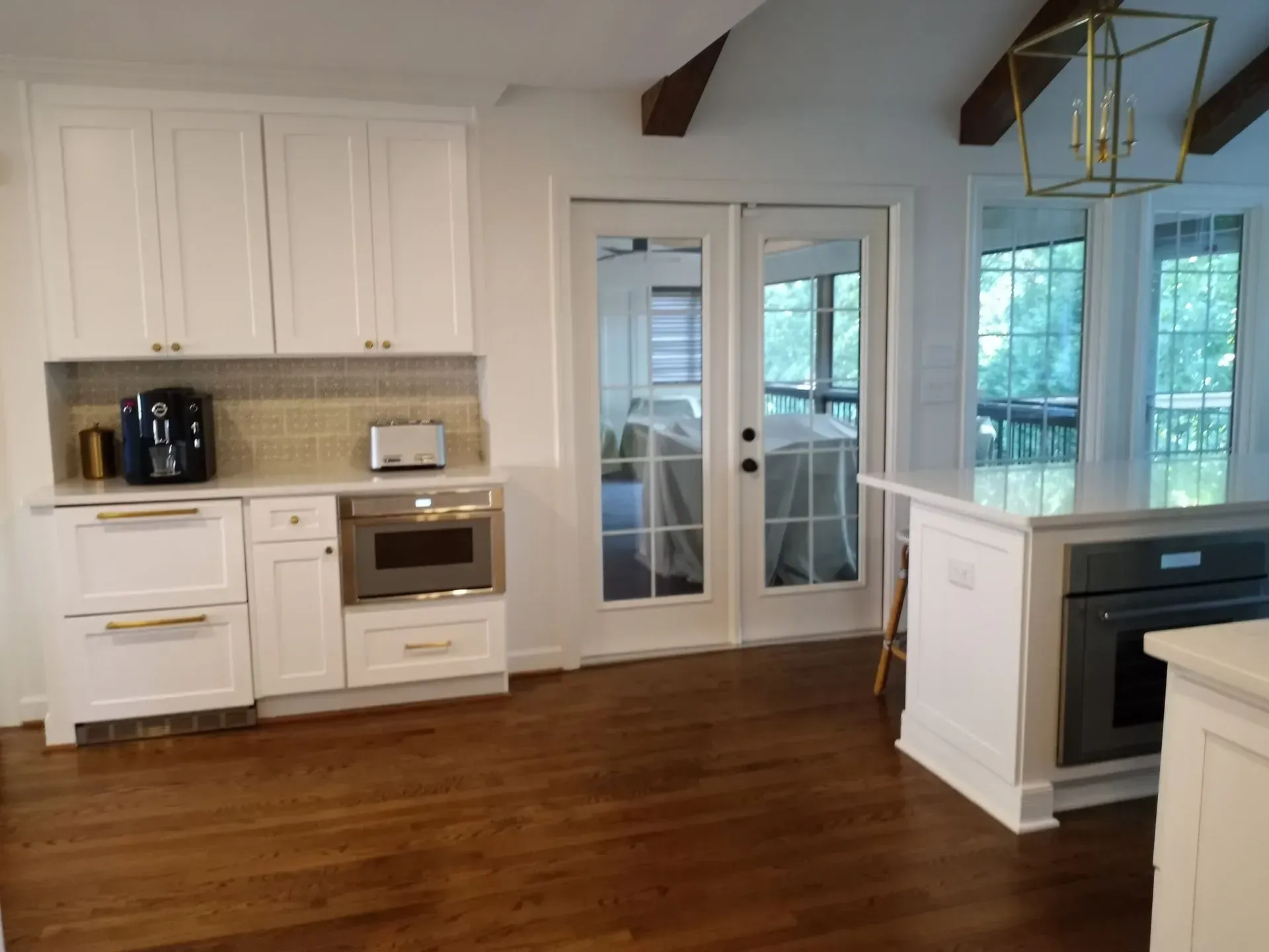 White kitchen with cabinets, double doors, island, and wood floor.