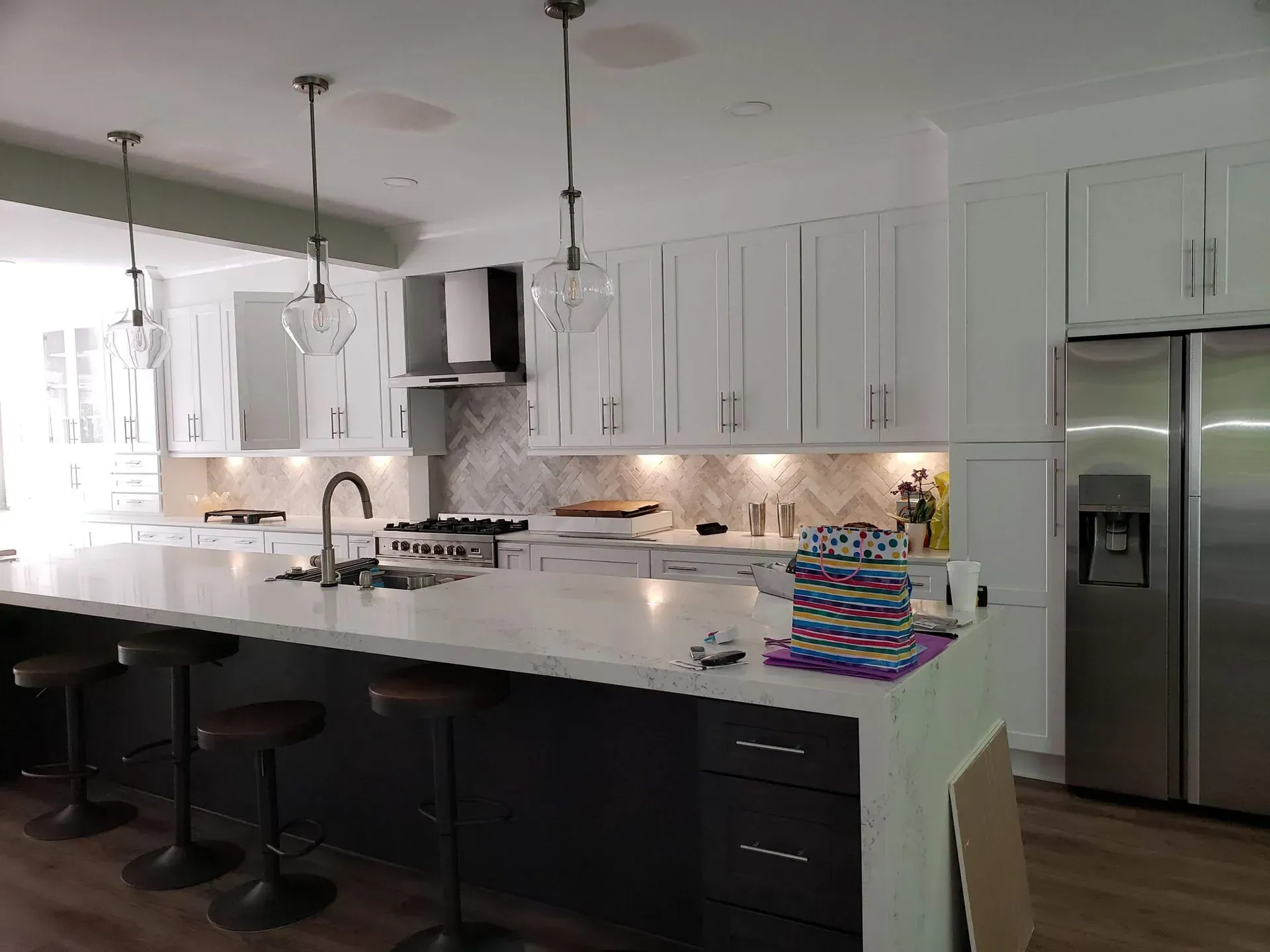 Modern kitchen with white upper cabinets, dark island, and stainless steel appliances.