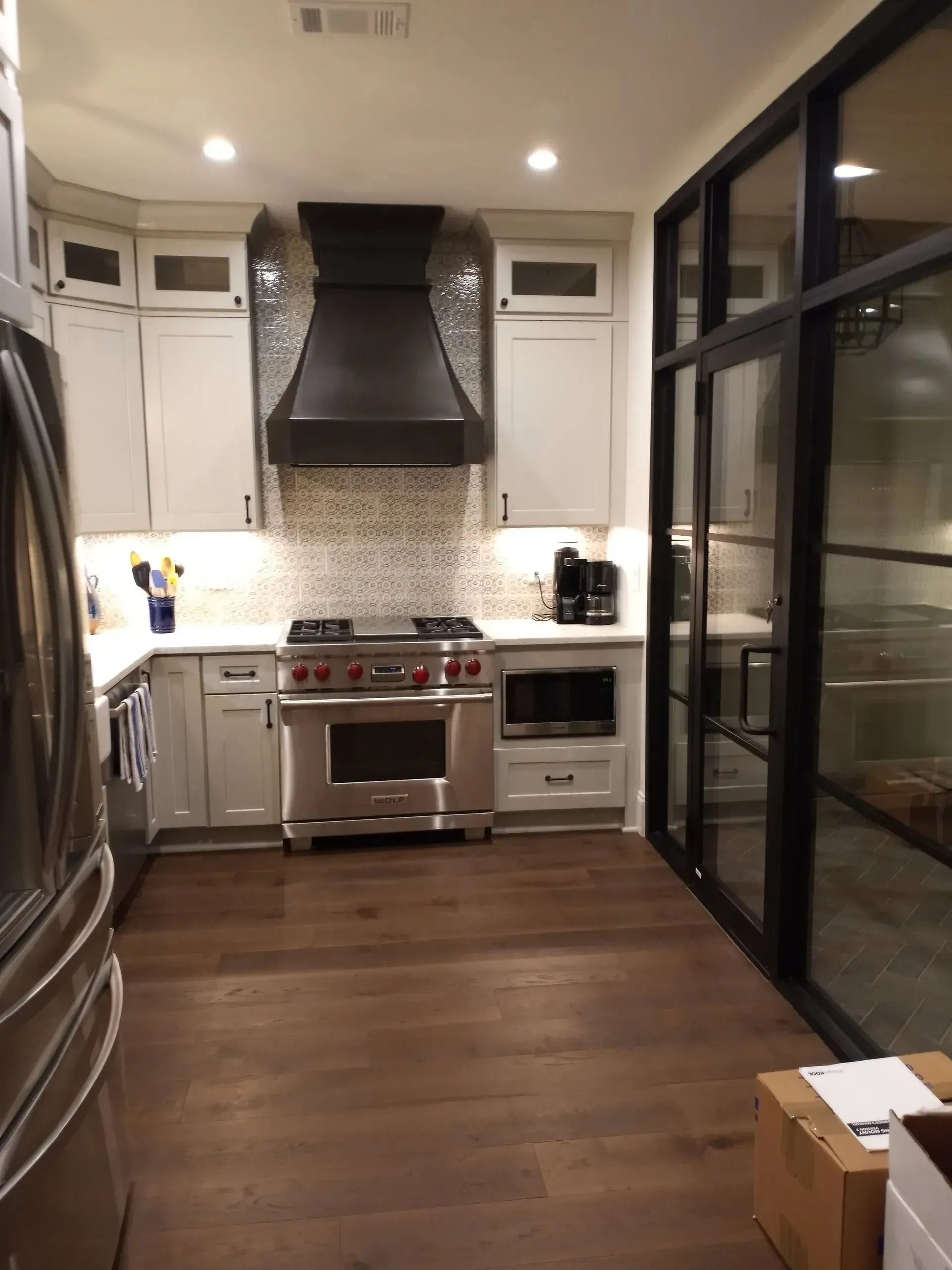 Modern kitchen with stainless steel appliances, grey cabinets, and dark wood floors.