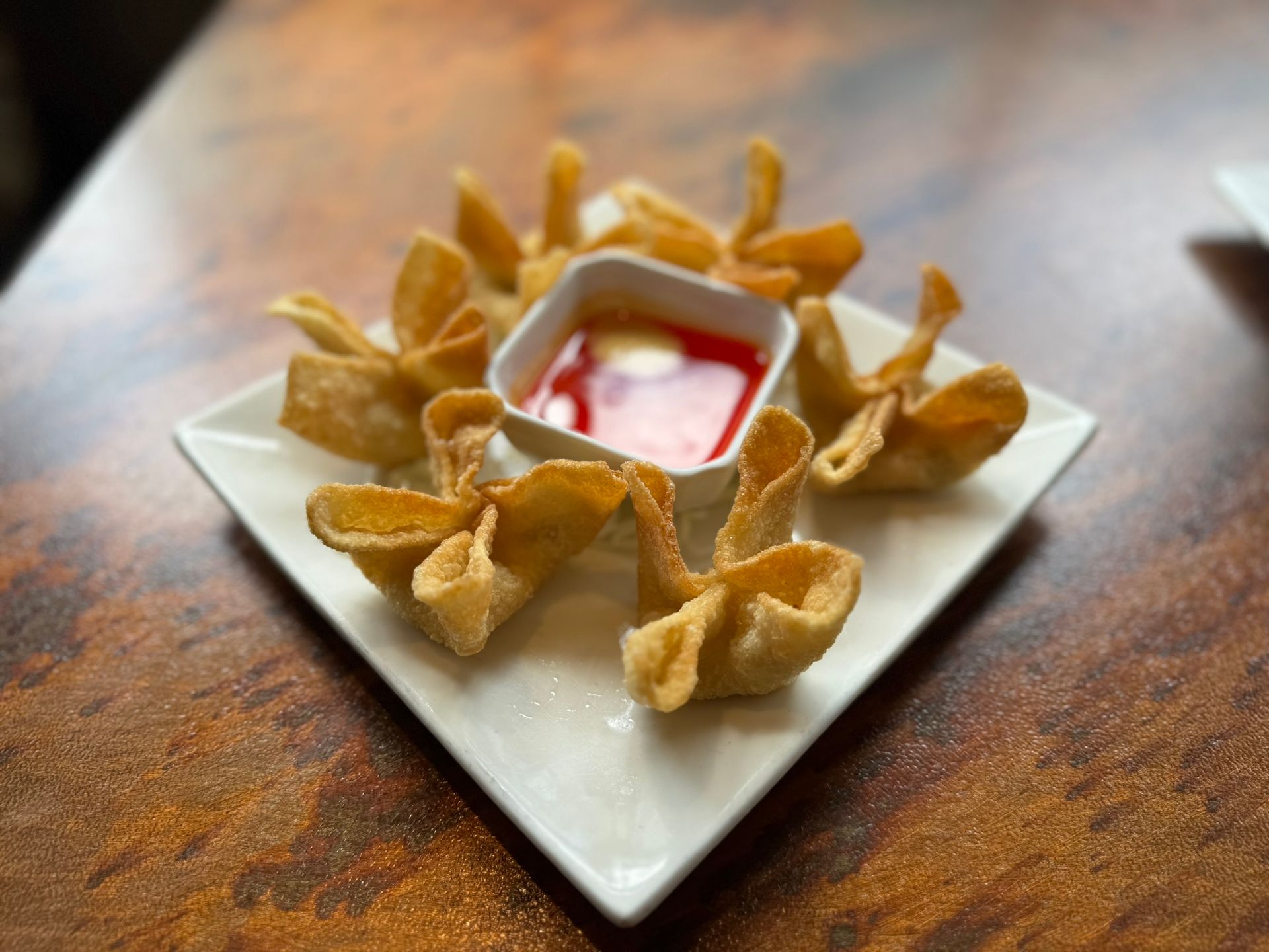 A white plate topped with fried food and a small bowl of dipping sauce.