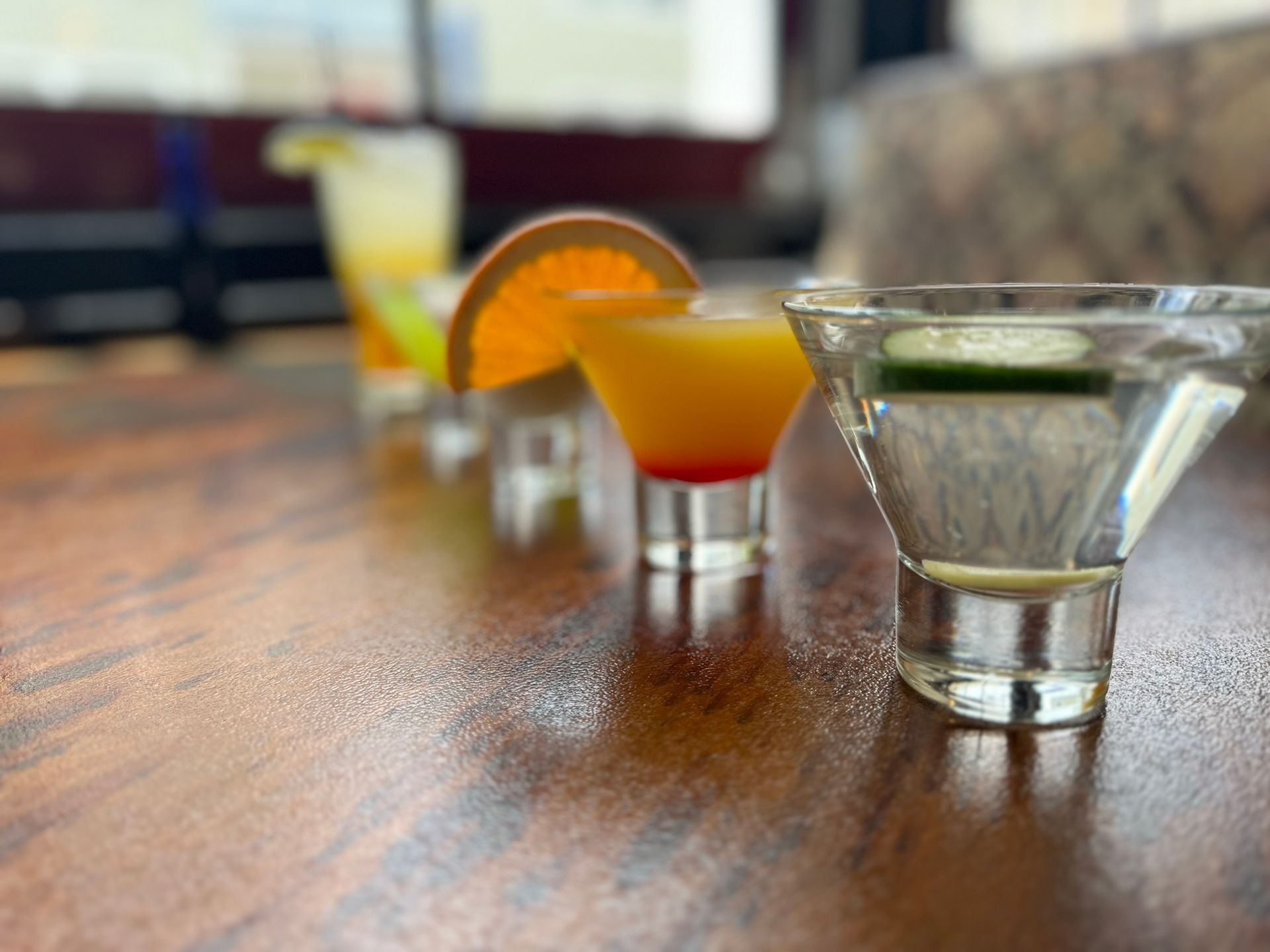 A row of shot glasses filled with different types of drinks on a wooden table.